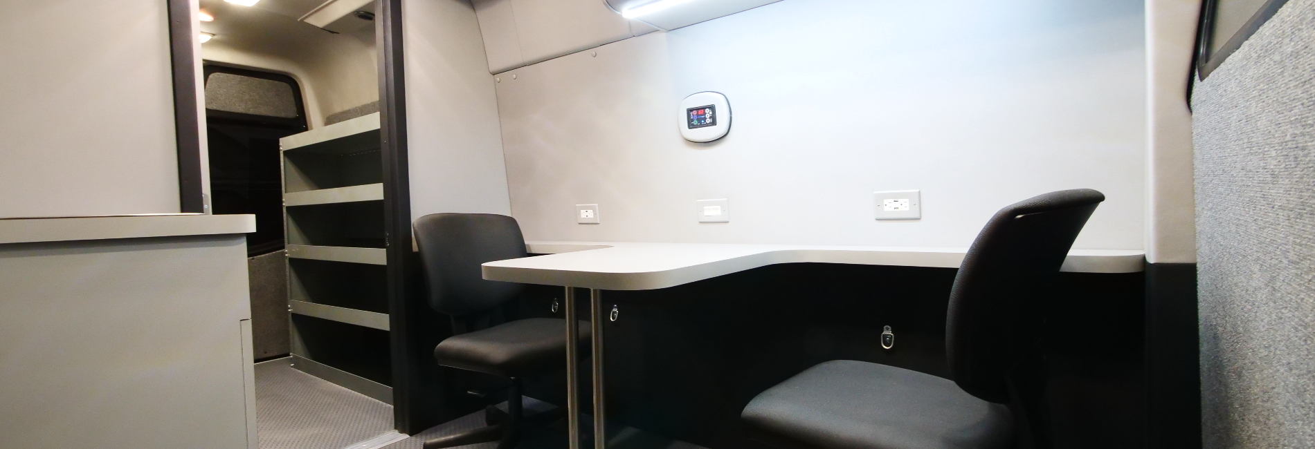 Dual mobile office layout consisting of a front workstation with a sink faucet and rear partition cargo area for equipment storage.